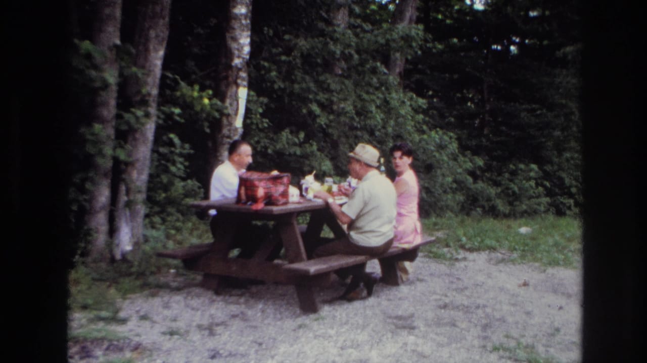 The home-movie frame shows three adults at a picnic table in a wooded Ottawa setting, with food containers and cups visible.