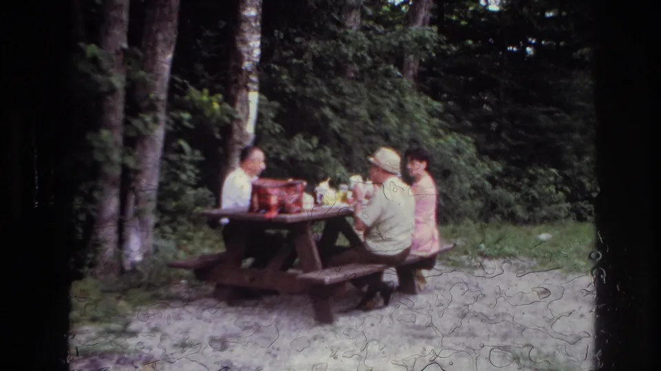 At the end of the clip, three adults sit at the wooden picnic table in the 1967 Ottawa home-movie scene, partly softened by film wear.