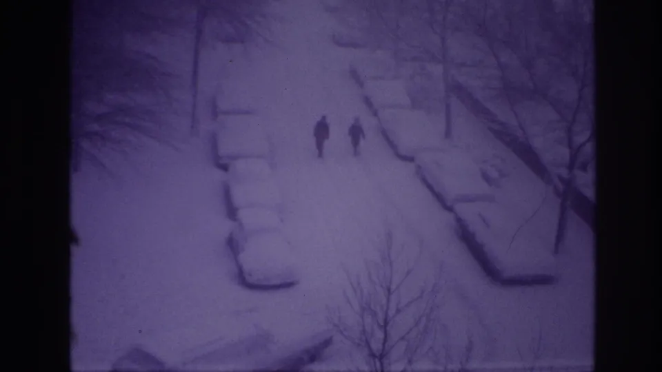 Distant pedestrians walk through a snowy Ottawa street scene from 1967, with cars buried under snow and bare trees nearby.