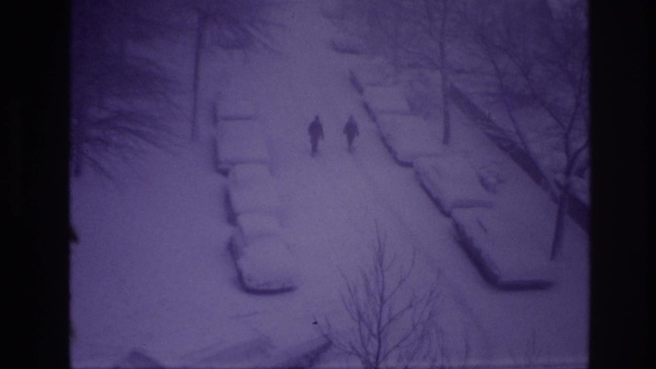 Ottawa 1967 home-movie frame showing two silhouettes on a snowy residential street viewed from above at night.