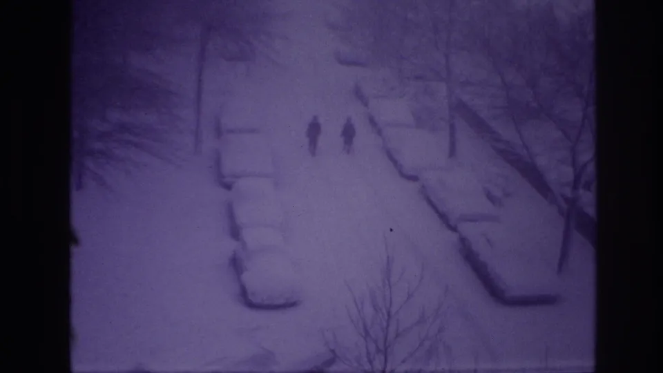 Purple-shifted 8mm frame from Ottawa showing two distant walkers on a snow-covered residential street at night.