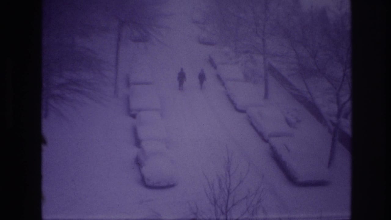High-angle 8mm view of two people walking through snow on an Ottawa residential street in 1967.
