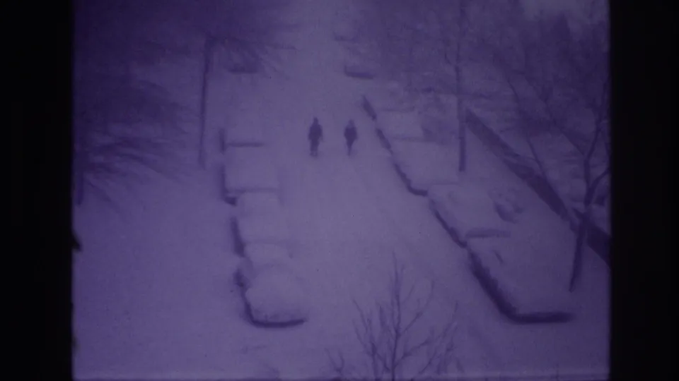 High-angle 8mm view of two people walking through snow on an Ottawa residential street in 1967.
