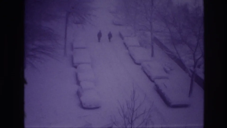 High-angle 1967 Ottawa winter frame showing two men walking on a snow-blanketed residential street.