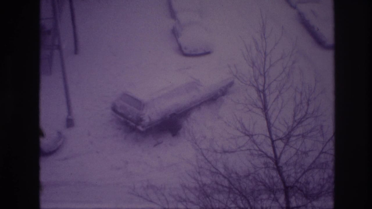 1967 Ottawa home-movie frame with a snow-buried car seen from above through bare winter branches.