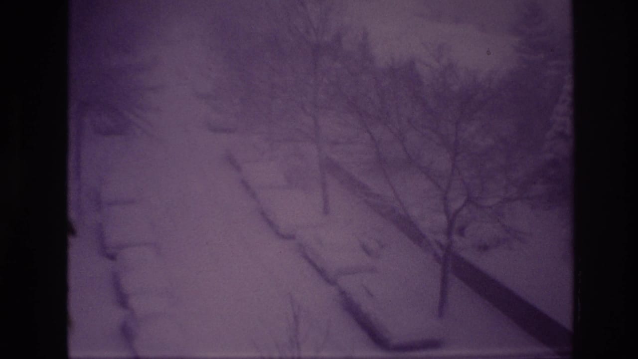 Final 1967 Ottawa frame of the snowstorm, with cars and curbs buried under snow and bare trees crossing the high-angle view.
