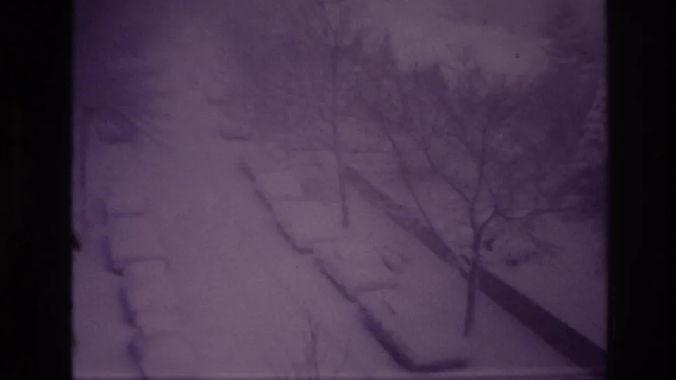 Final 1967 Ottawa frame of the snowstorm, with cars and curbs buried under snow and bare trees crossing the high-angle view.