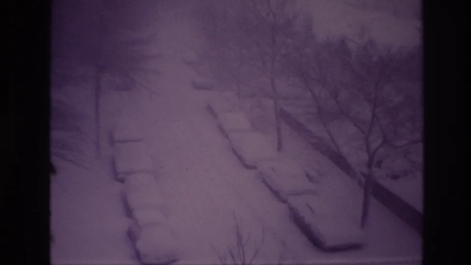 1967 Ottawa 8mm frame of a snowed-in residential street, where parked cars are mostly reduced to rounded shapes under heavy snow.