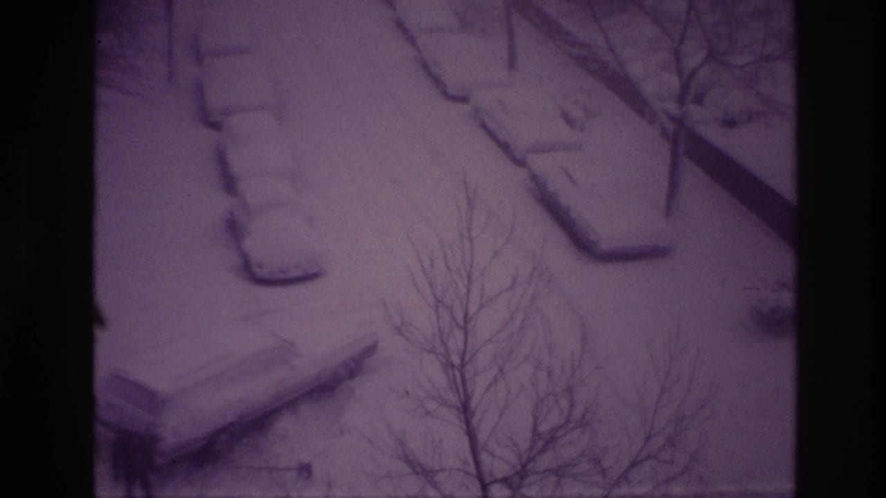 Ottawa 1967 home-movie frame of a snow-covered parking area, parked cars, and leafless branches seen from above.