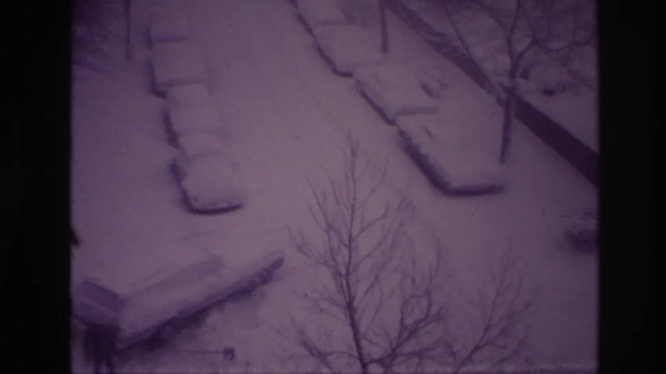 Ottawa 1967 home-movie frame of a snow-covered parking area, parked cars, and leafless branches seen from above.