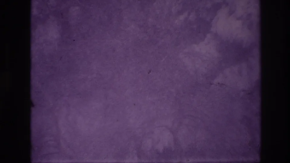 Purple-tinted 8mm frame with dark film borders, mottled exposure, and no distinct subject visible.