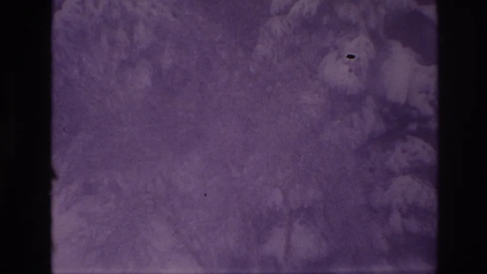 Purple-tinted 8mm frame with cloudy exposure patterns, grain, specks, and a dark vertical film border.