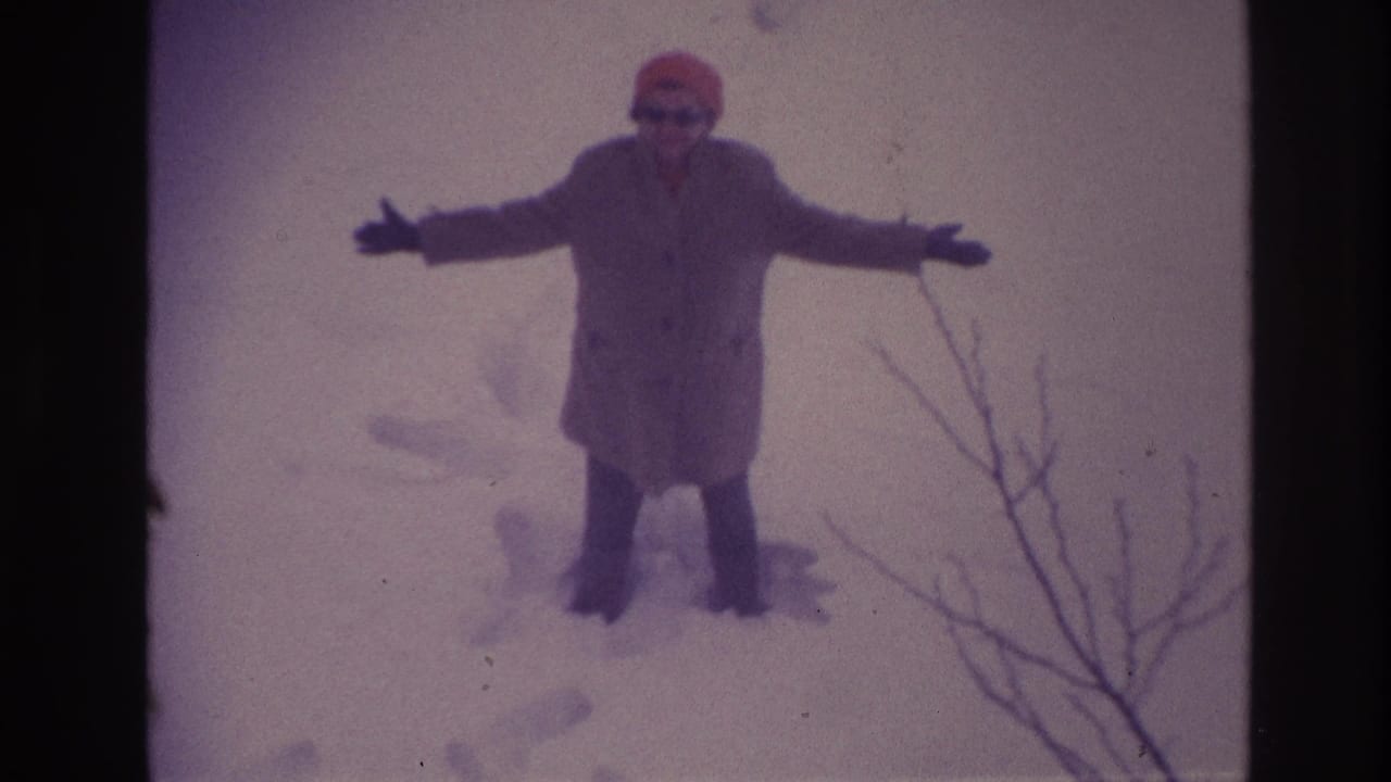 Woman in deep snow holds both arms out while snow obscures the background.