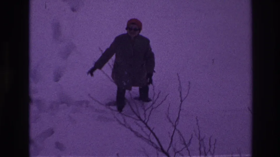 A person in a heavy coat and red hat moves through deep Ottawa snow, with bare branches visible in the foreground.