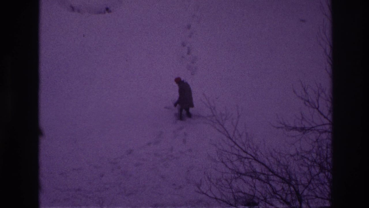 In Ottawa 1967 home-movie footage, a distant man in dark winter clothing walks through deep snow beside bare branches.