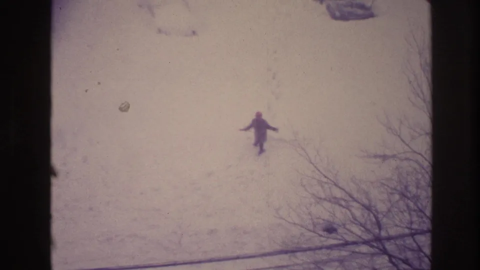 1967 Ottawa 8mm frame looking down at a distant person in snow, with footprints, bare branches, and soft faded color.