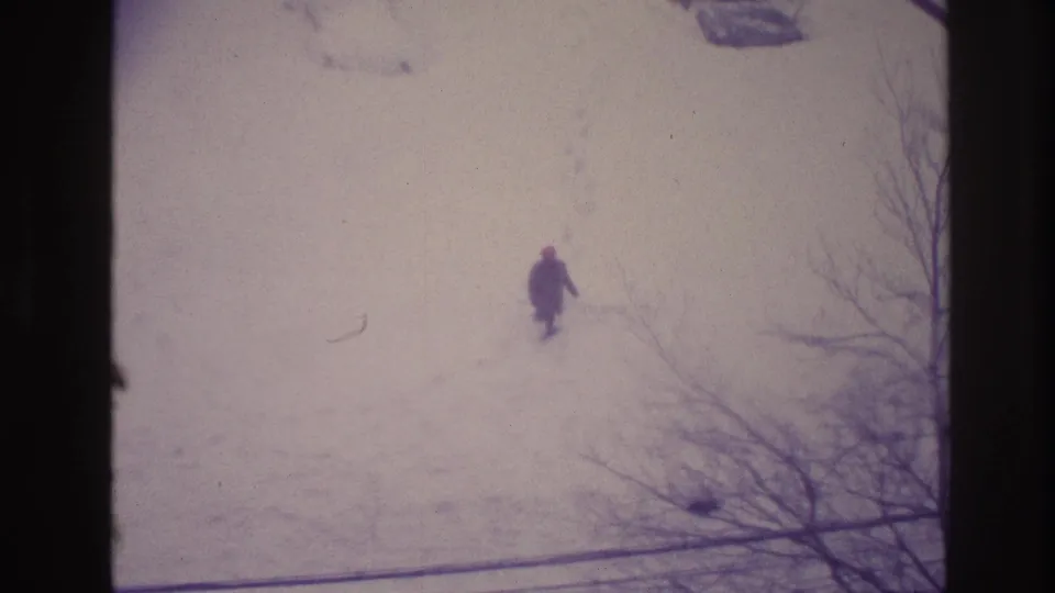 Faded 8mm Ottawa winter frame showing a distant person walking through snow with footprints trailing behind.