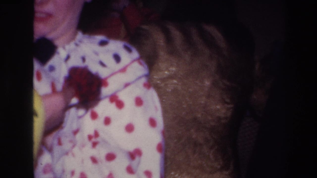 Ottawa 1967 home-movie frame showing a partial close view of a woman in a white polka-dot clown costume inside a dim party room.