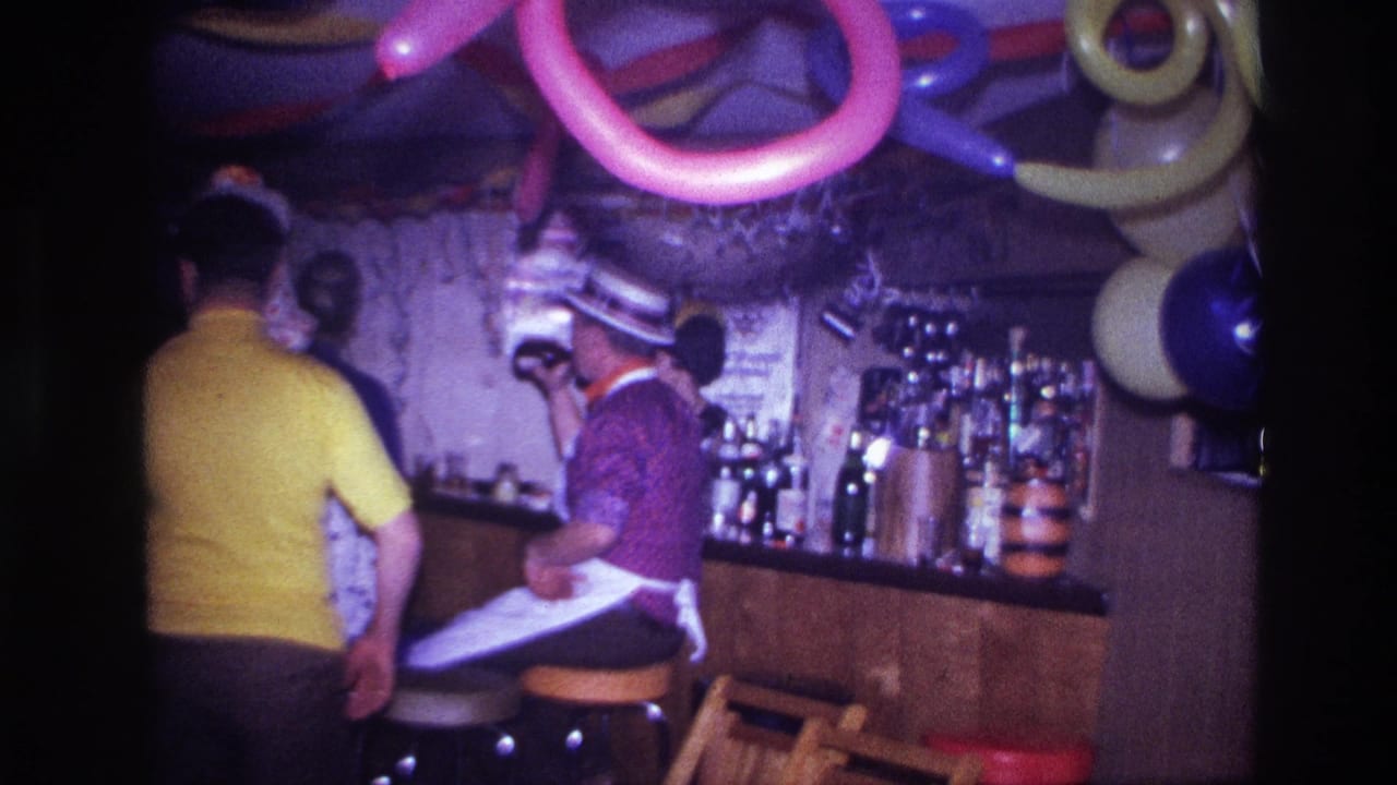 Ottawa 1967 frame with adults in novelty hats near a wood bar, hanging balloons, streamers, bottles, and stools.