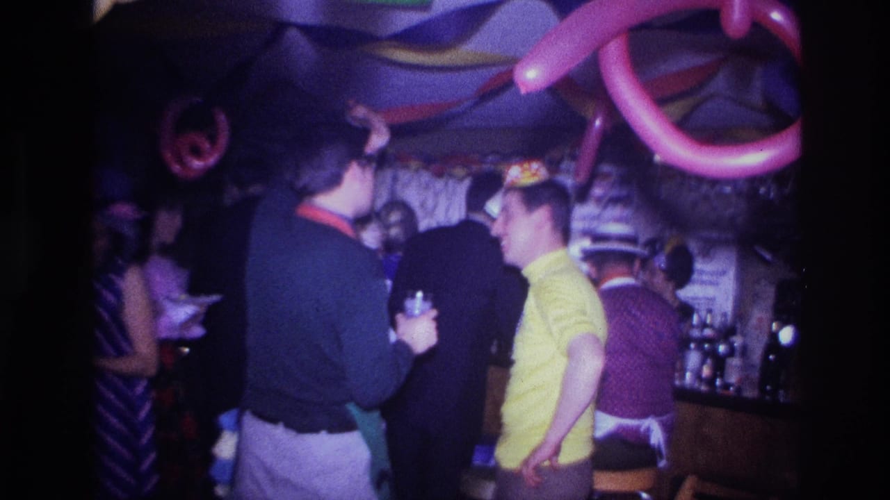 Guests mingle under balloon decorations in a crowded party room.
