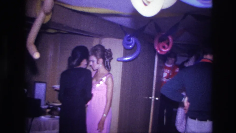 1967 Ottawa party frame with a woman in a pink dress facing another guest while balloons and streamers hang overhead.