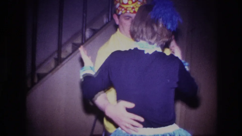 The costumed man faces the camera while holding his partner near a staircase in the Ottawa 1967 home-movie scene.