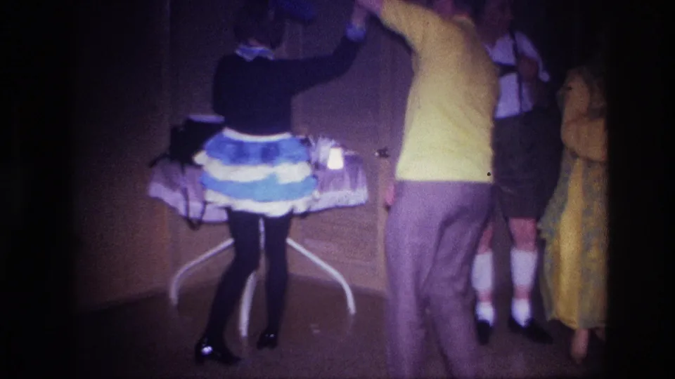 Seen from behind, the couple dances across the Ottawa party room as guests in costume remain near the wall and refreshment table.