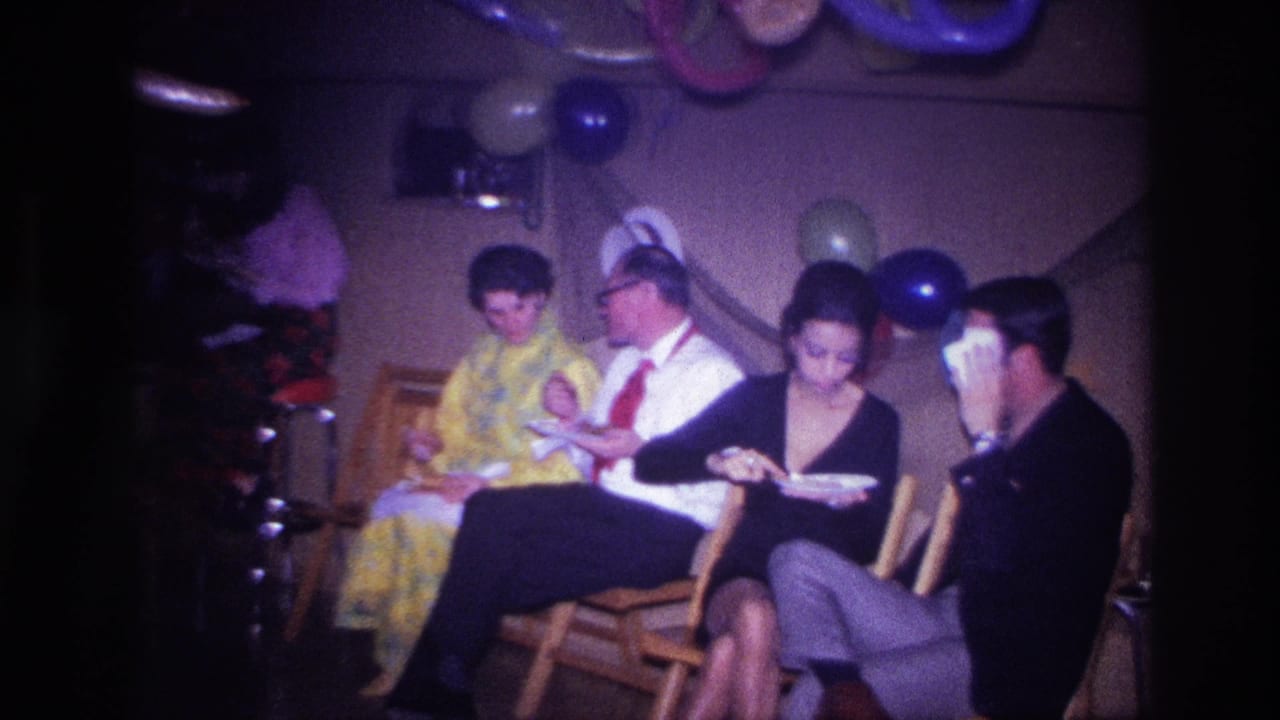 Adults at a 1967 Ottawa indoor party sit under balloons and streamers while eating from paper plates in a private room.