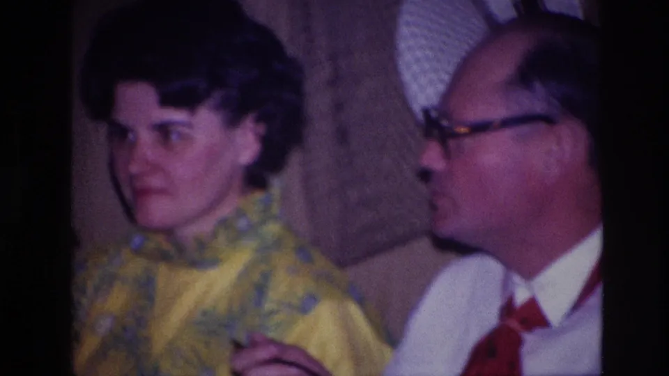 Close Ottawa 1967 frame of two seated adults in conversation during a private indoor birthday gathering.