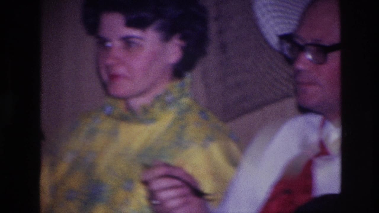 1967 Ottawa home-movie frame showing a formally dressed woman and man seated in a restaurant booth.