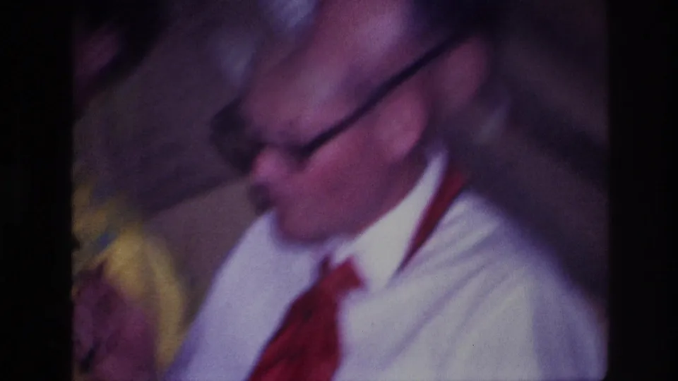 Close 8mm frame from the Ottawa restaurant scene showing the man in glasses near plates and food.