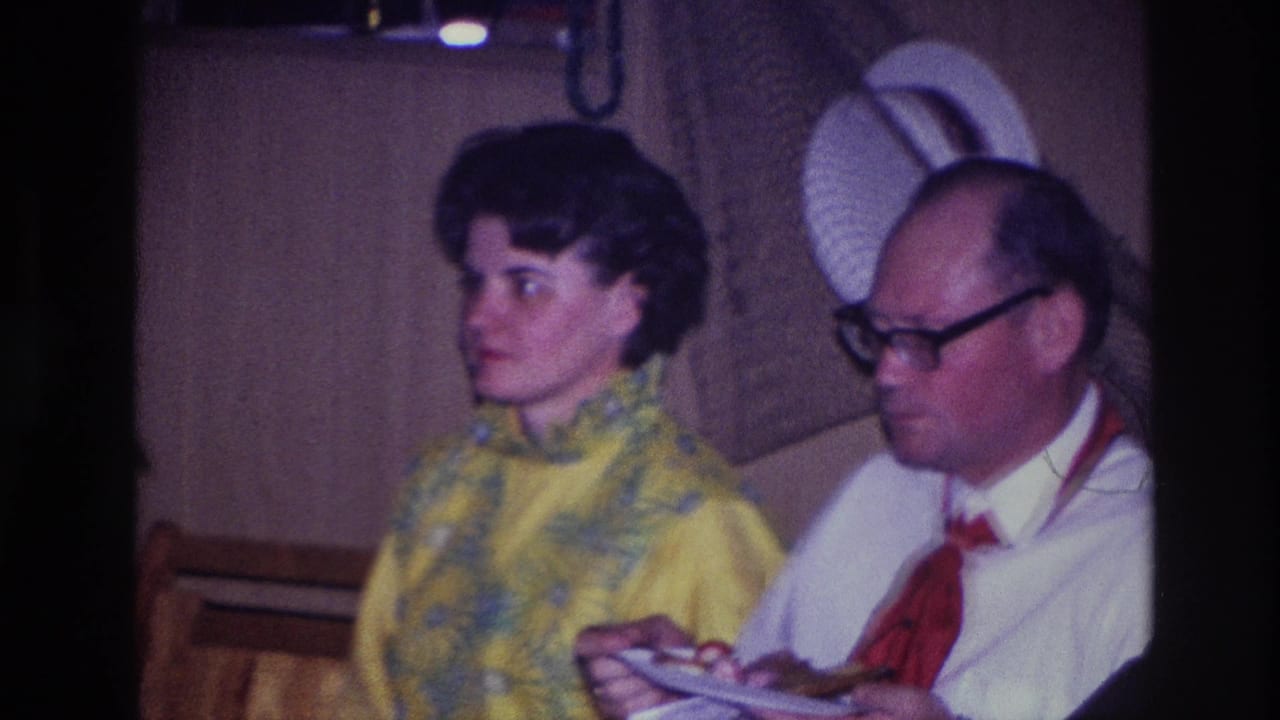 Seated woman and man eating from plates in a private room.