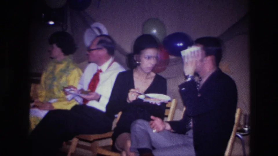 A wider 1967 Ottawa party view shows several adults seated with plates, with colorful balloons behind them in a private interior.