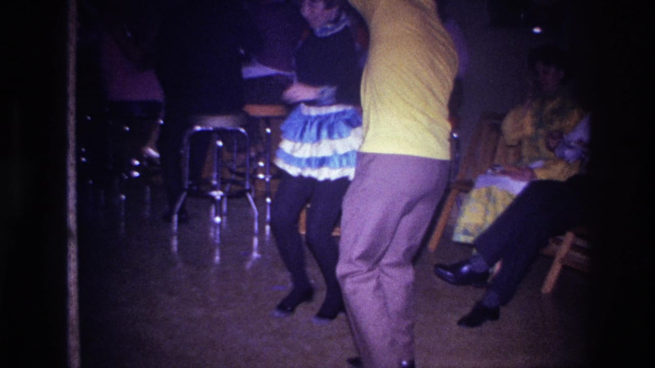 1967 Ottawa 8mm footage shows a man in a yellow shirt dancing with a woman in a ruffled skirt in a dim party interior.