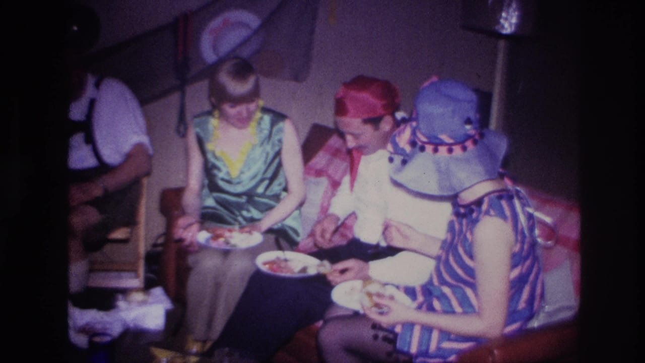 Three costumed adults eat from plates while seated near party decorations.
