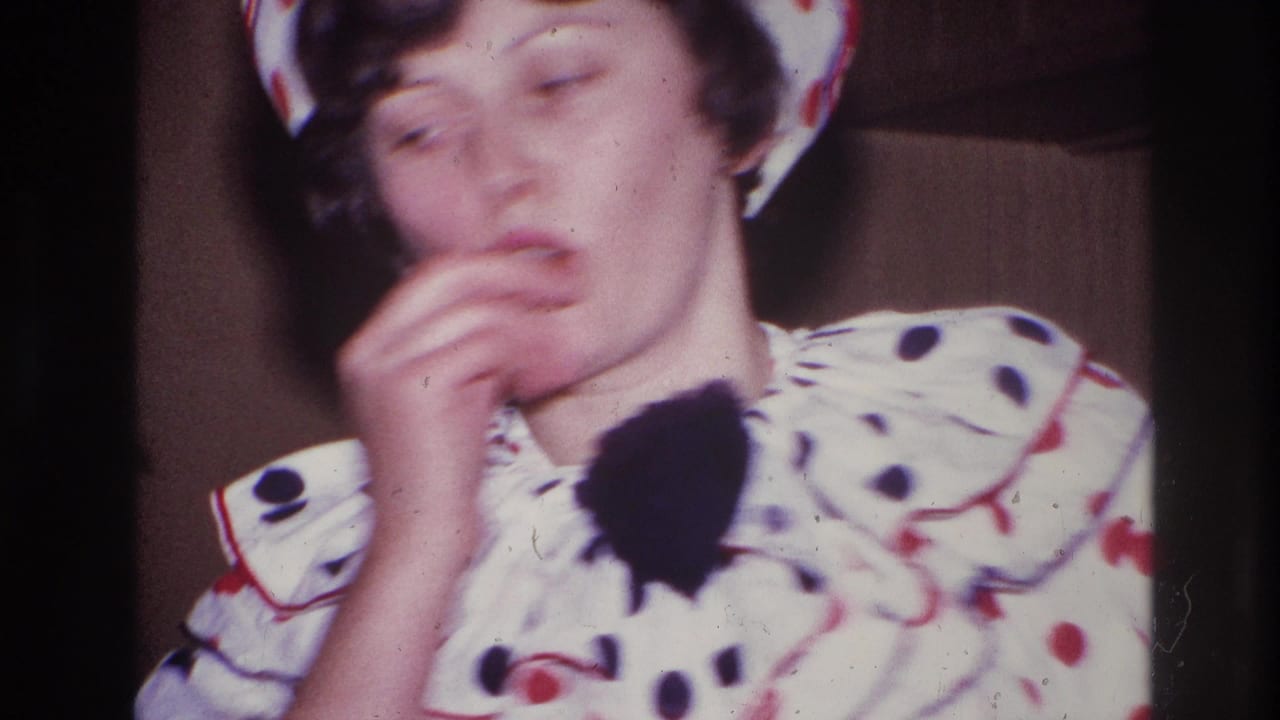 Close 1967 Ottawa home-movie frame of an adult in a white clown costume with red and black dots, partly blurred while raising a hand near the face.