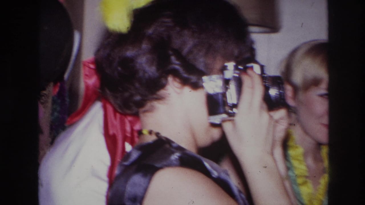 Close side view of a woman aiming a camera beside other party guests.