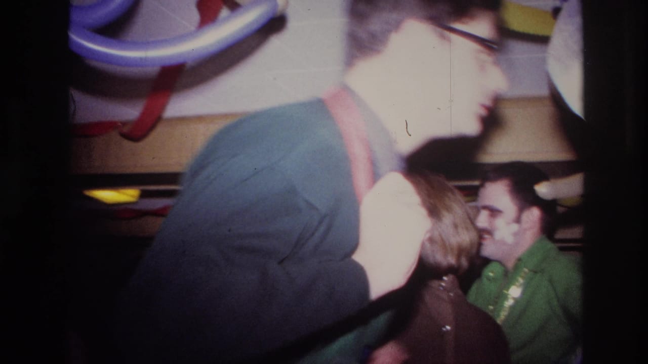 Man in dark clothing moves past guests at a crowded indoor party.
