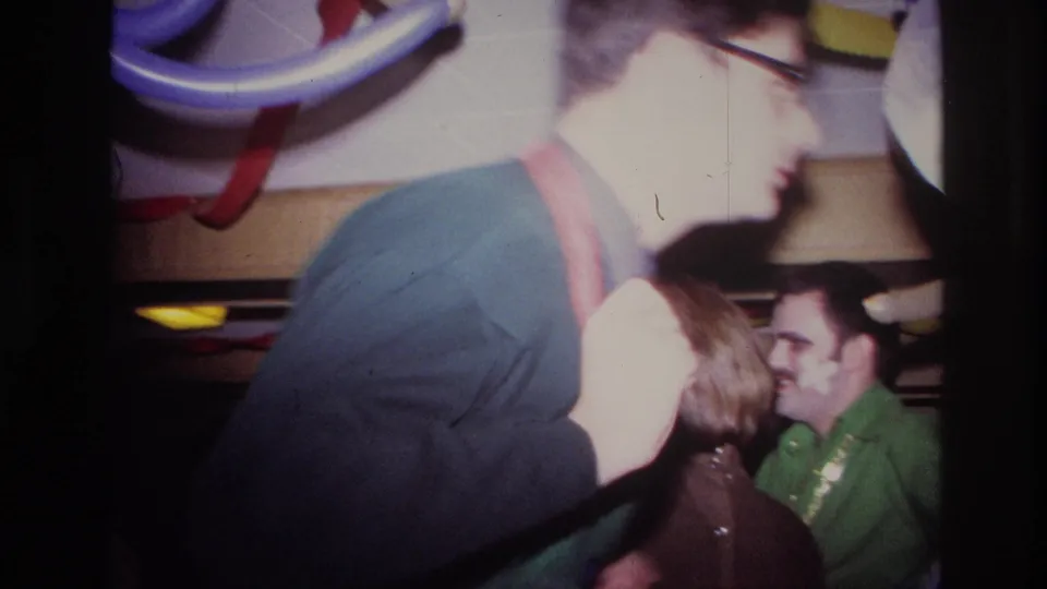 Flash-lit 1967 Ottawa party frame with a man moving past other adult guests in a decorated interior.