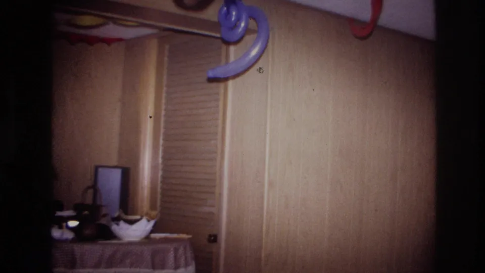 1967 Ottawa home-movie frame focused on a decorated private interior with wood paneling, streamers, and a table of items.