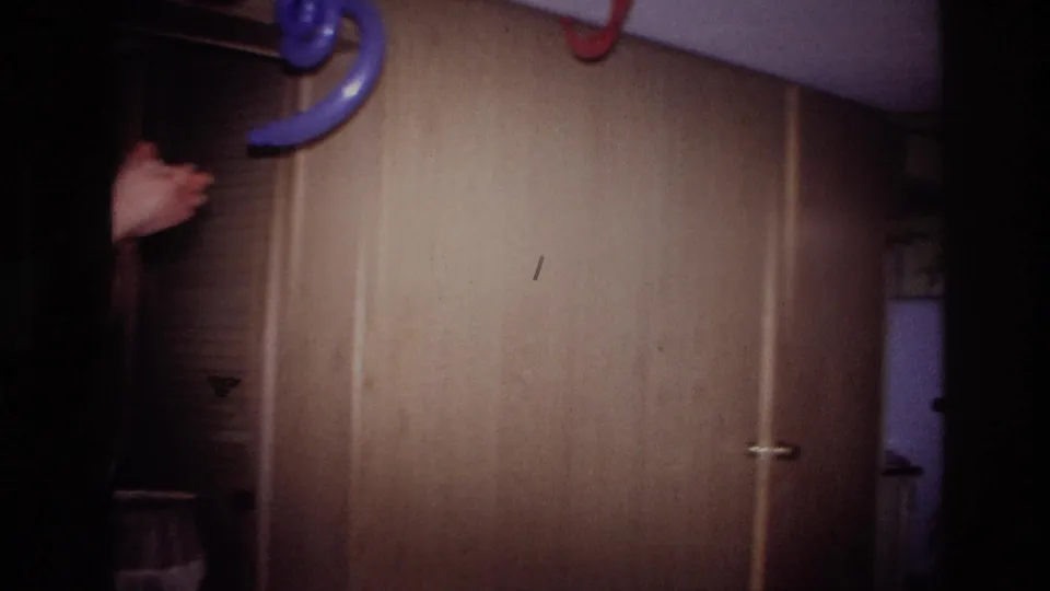 1967 Ottawa home-movie frame showing the decorated interior wall with streamers and a partial guest at the edge.