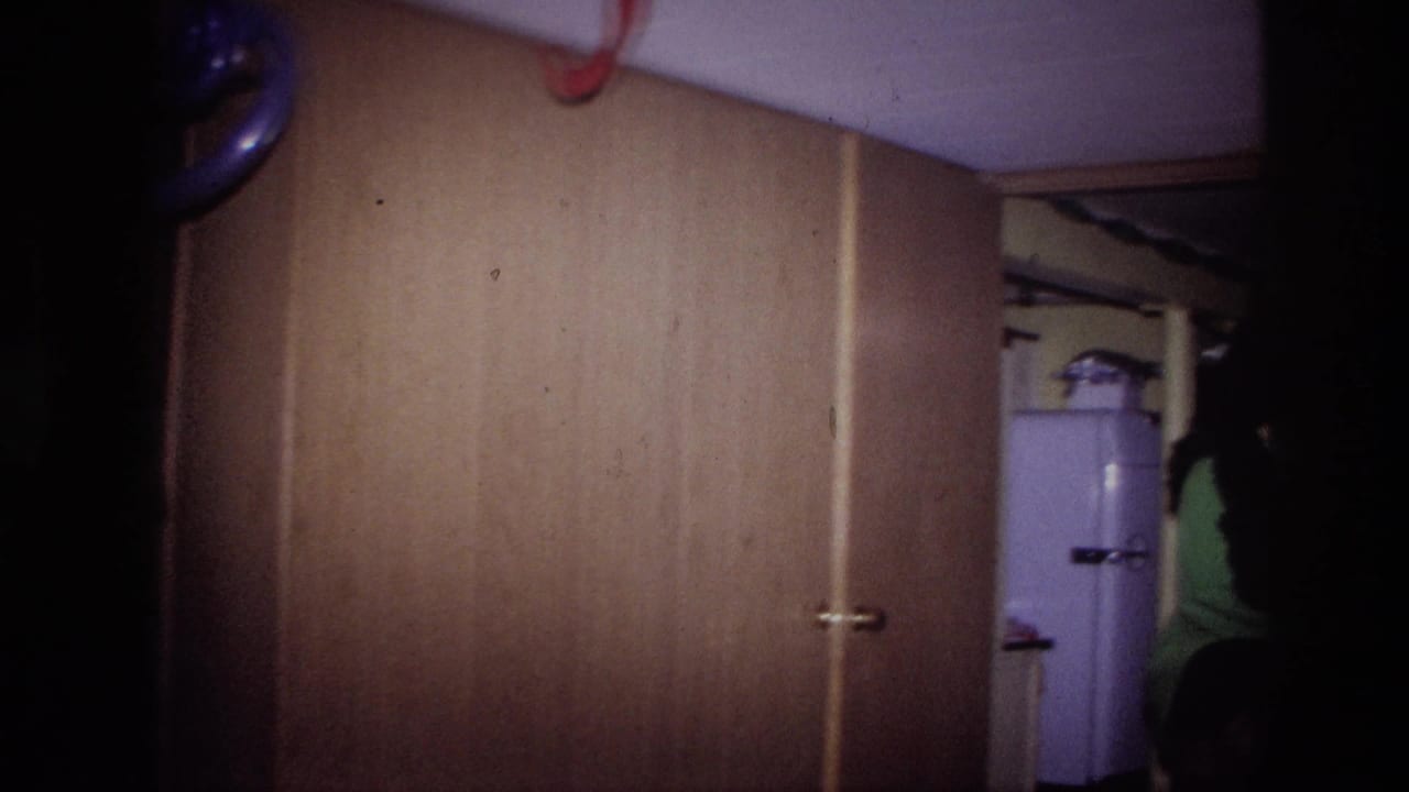 Wood-paneled interior with a white refrigerator partly visible in the background.