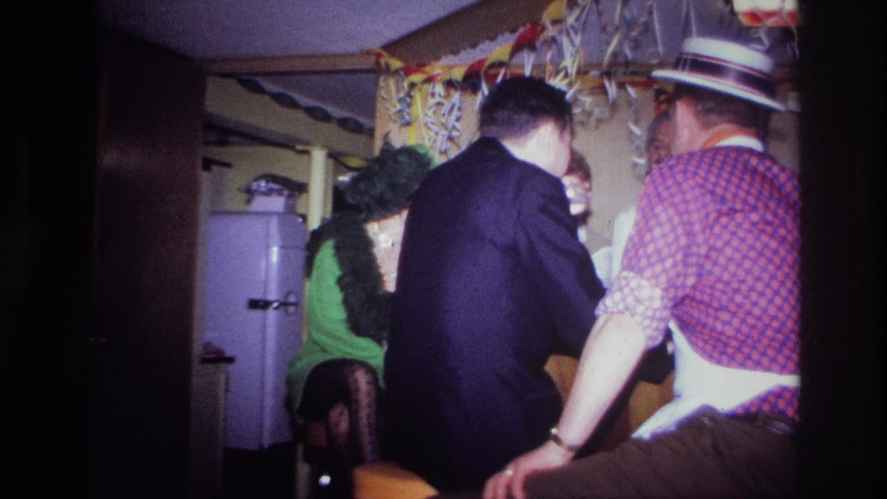 1967 Ottawa home-movie frame showing adults at a decorated indoor bar, including a man in a dark suit and another in a straw hat.