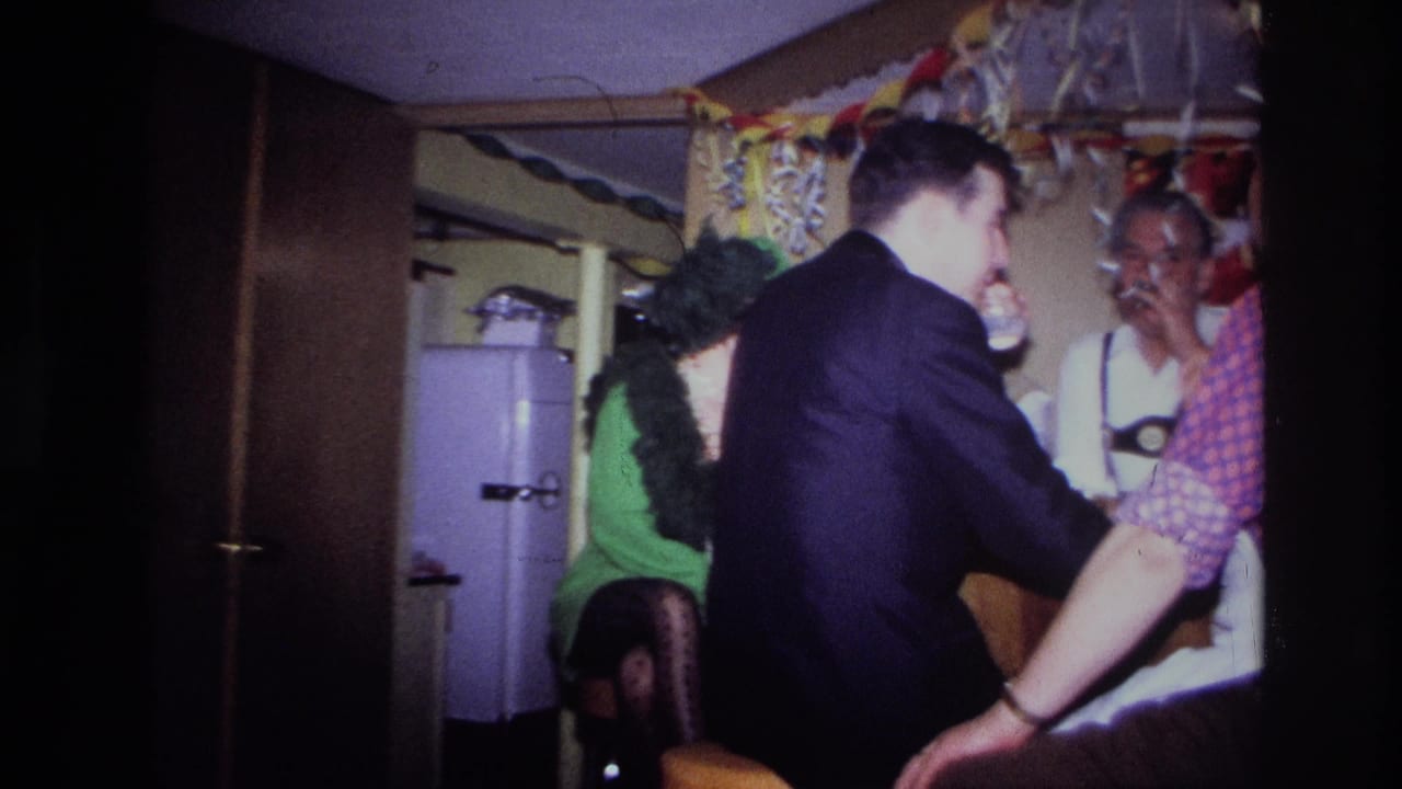 Adult guests talking at a decorated indoor party near a white refrigerator.