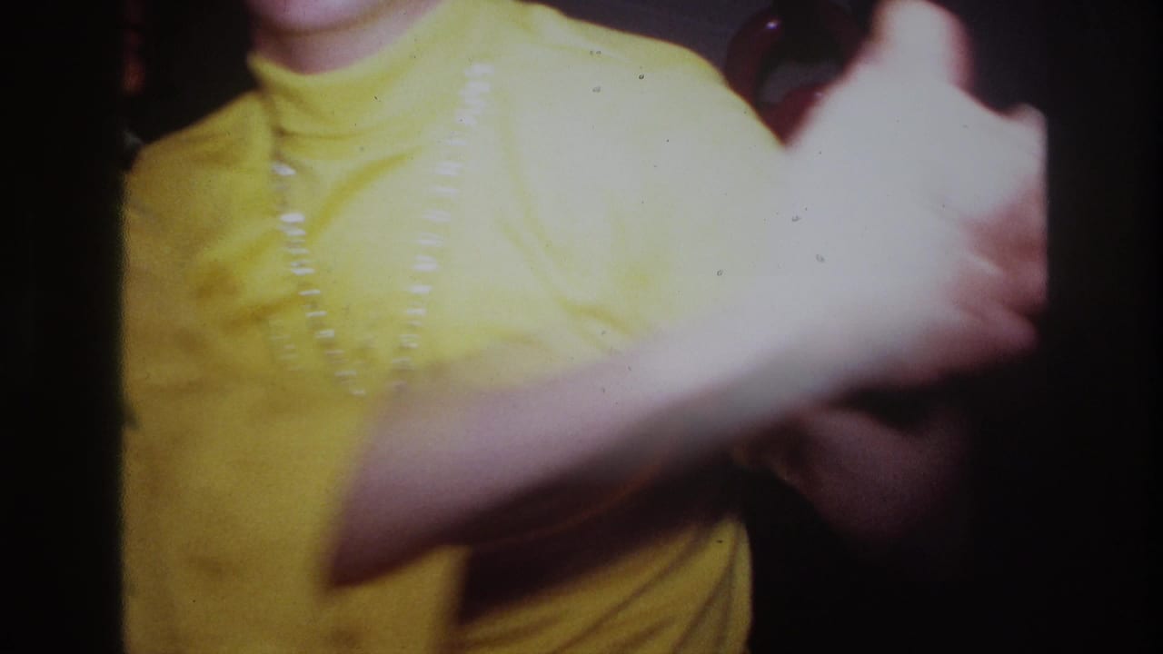 Ottawa 1967 home-movie frame showing a yellow-turtlenecked adult dancing closely, with soft focus and dark film edges.