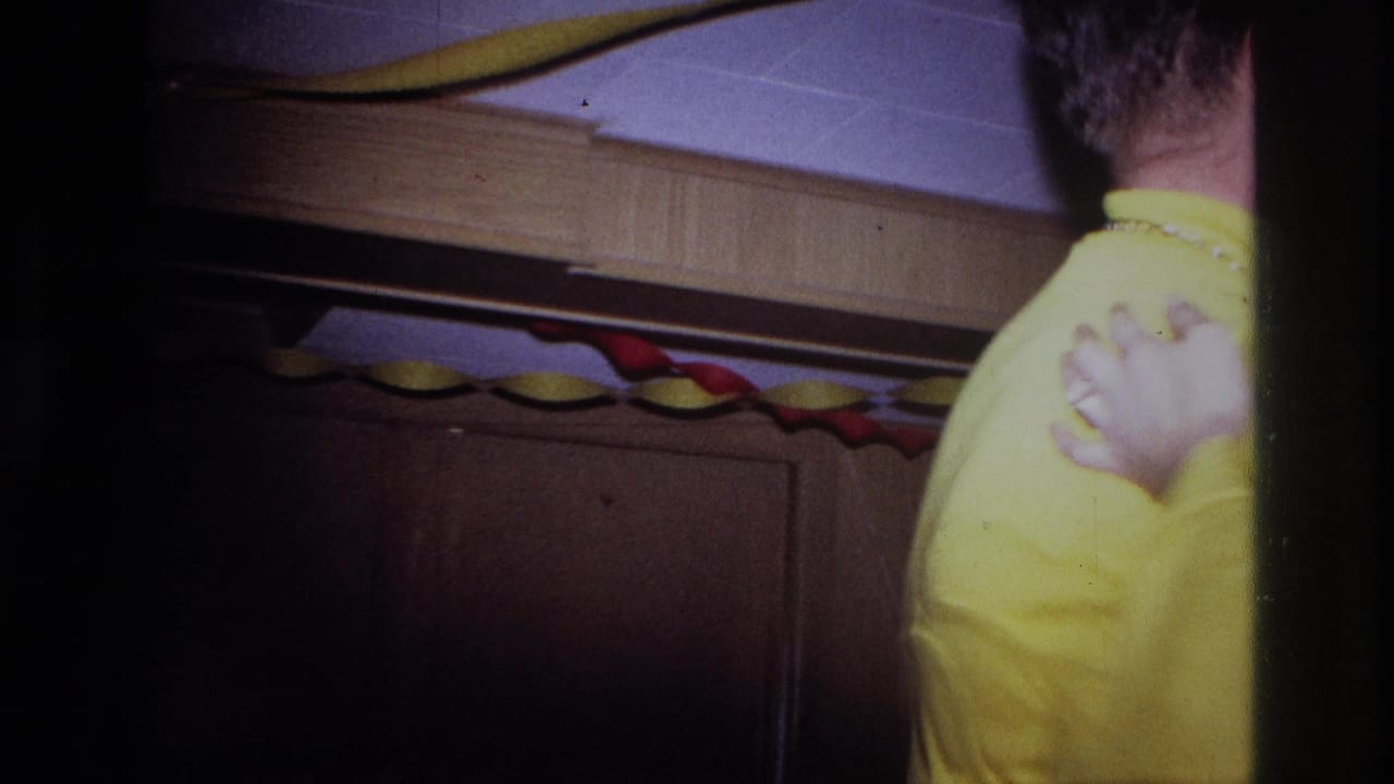 Back of a person in yellow near wood paneling and paper garlands.