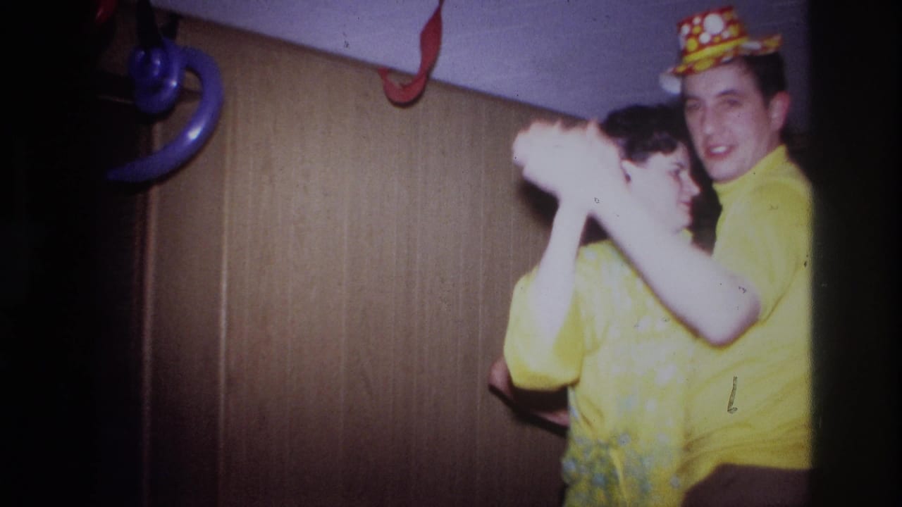 Young couple in yellow clothing dancing closely beside party decorations.