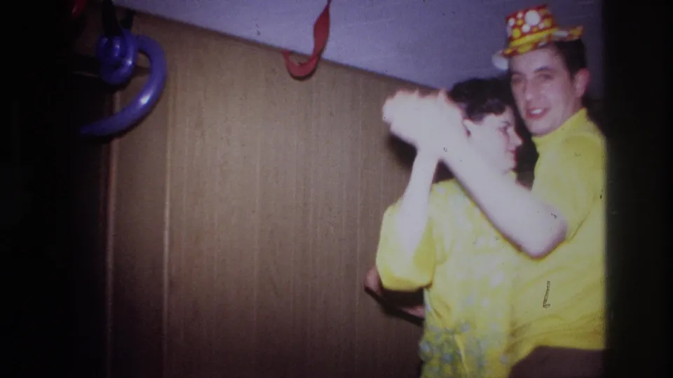 In 1967 Ottawa home-movie footage, a young couple dances closely in a dim room with balloon decorations and a party hat visible.