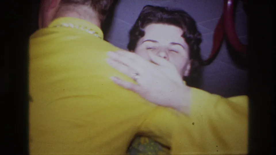 A close handheld frame shows the woman smiling as she embraces her dance partner inside the decorated private party room.
