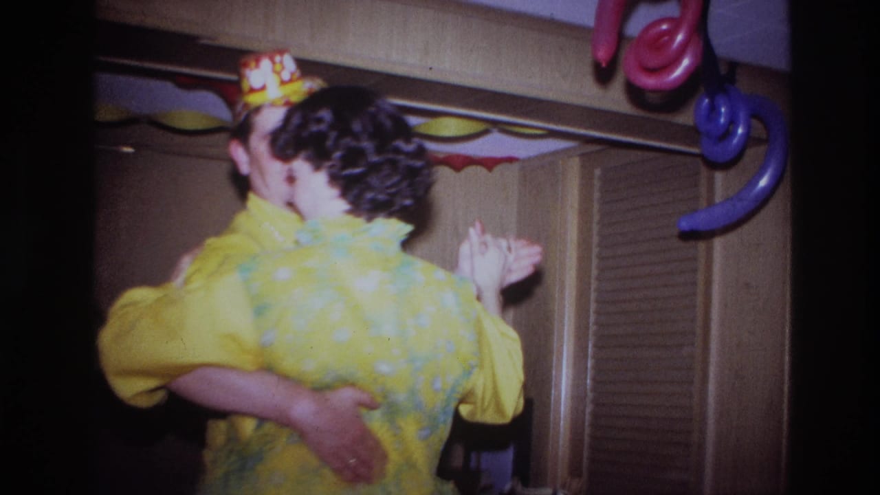 In a 1967 Ottawa home-movie frame, a young man and his mother dance under paper streamers and balloons in a decorated room.